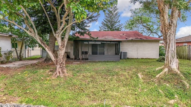 rear view of house featuring a sunroom, a yard, and cooling unit