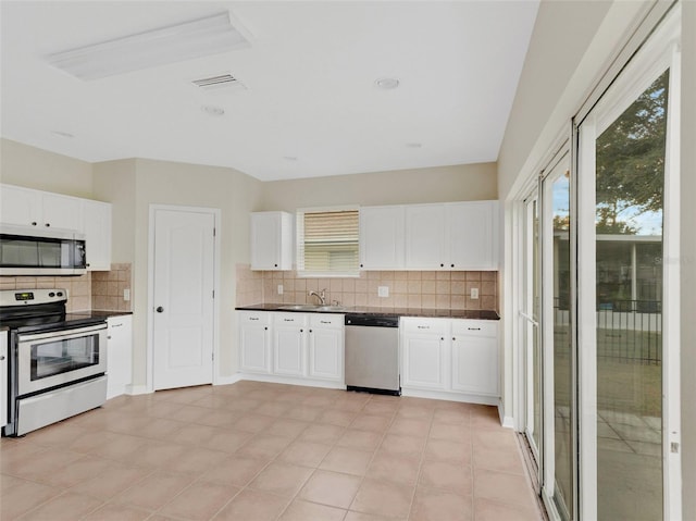 30619 White Bird Ave, Wesley Chapel, FL 33543 - kitchen with stainless steel appliances, dark countertops, decorative backsplash, white cabinets, and a sink