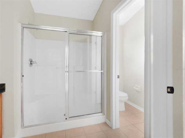 bathroom featuring tile patterned flooring, toilet, and walk in shower