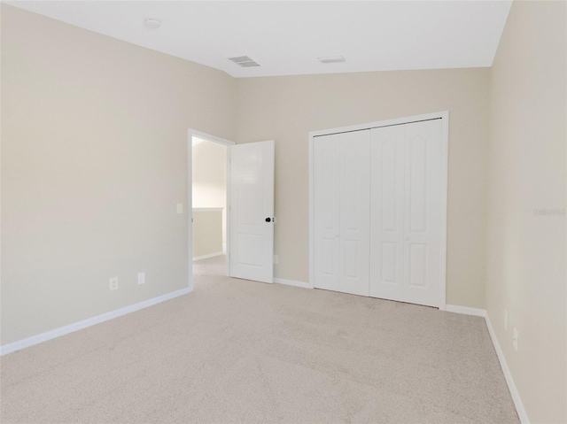 unfurnished bedroom featuring a closet, light colored carpet, and vaulted ceiling