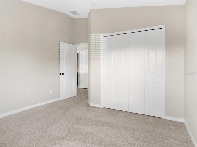 unfurnished bedroom with light carpet, a closet, and lofted ceiling