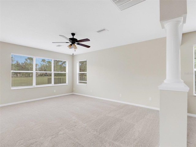 carpeted empty room featuring ornate columns and ceiling fan