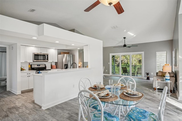 dining room featuring ceiling fan, sink, light hardwood / wood-style floors, and lofted ceiling