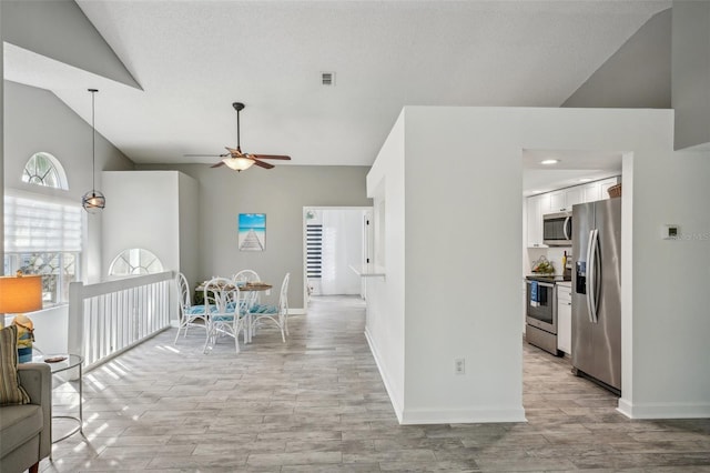 interior space with ceiling fan, light hardwood / wood-style floors, lofted ceiling, and appliances with stainless steel finishes