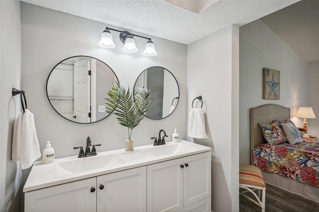 bathroom featuring vanity, wood-type flooring, a textured ceiling, and lofted ceiling