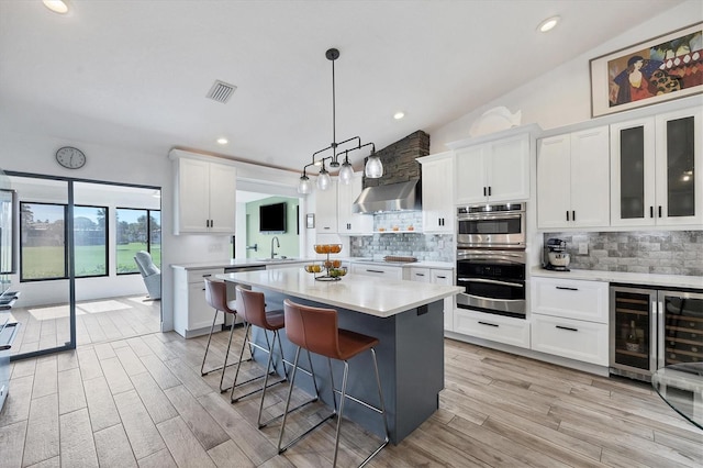 kitchen with lofted ceiling, a breakfast bar, extractor fan, beverage cooler, and white cabinets