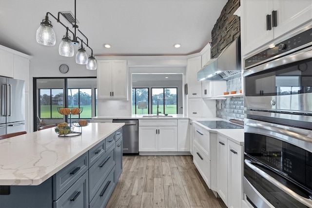 kitchen featuring pendant lighting, stainless steel appliances, light hardwood / wood-style flooring, and white cabinets