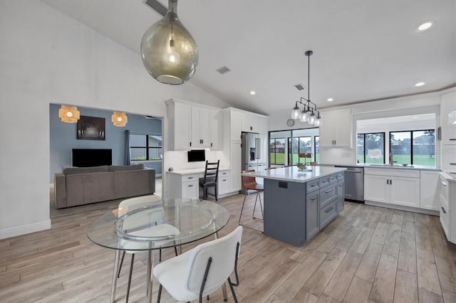 kitchen with a kitchen island, a breakfast bar, appliances with stainless steel finishes, gray cabinetry, and white cabinets