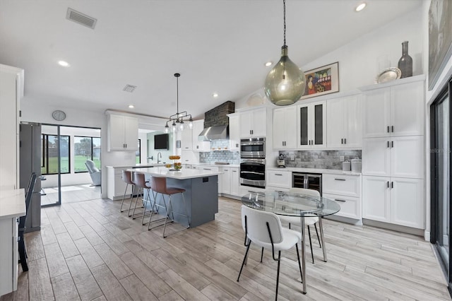 kitchen featuring wine cooler, hanging light fixtures, white cabinets, and a kitchen island