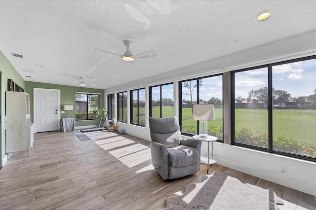 unfurnished sunroom with ceiling fan