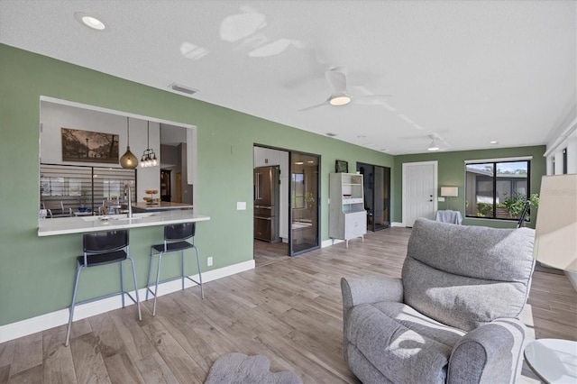 living room with sink, a textured ceiling, wood-type flooring, and ceiling fan