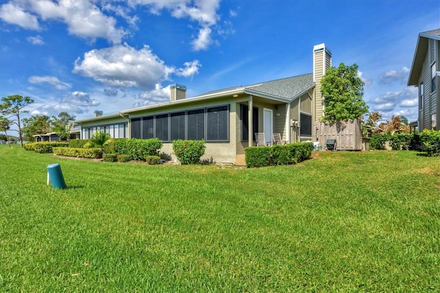 rear view of property featuring a sunroom and a lawn