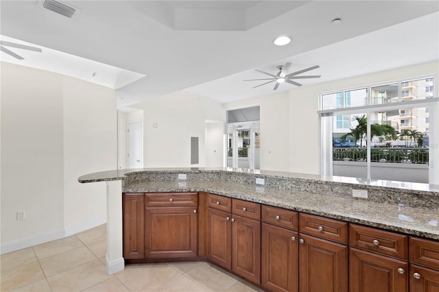 450 Knights Run Ave Unit 407, Tampa, FL 33602 - kitchen featuring ceiling fan, light stone countertops, light tile patterned floors, brown cabinets, and baseboards