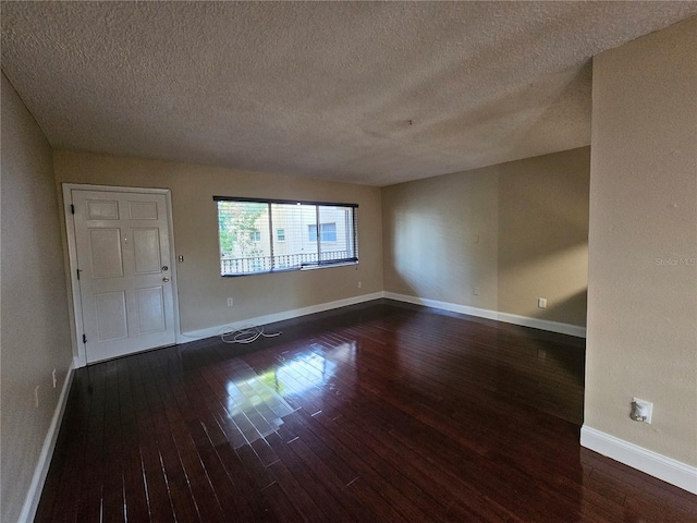 unfurnished room with dark wood-style floors, a textured ceiling, and baseboards