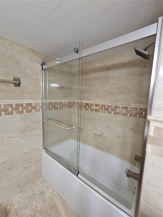 full bath with a textured ceiling, shower / bath combination with glass door, and tile patterned flooring