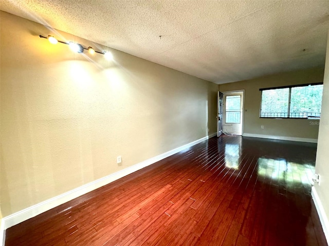 unfurnished room featuring baseboards, a textured ceiling, and hardwood / wood-style floors