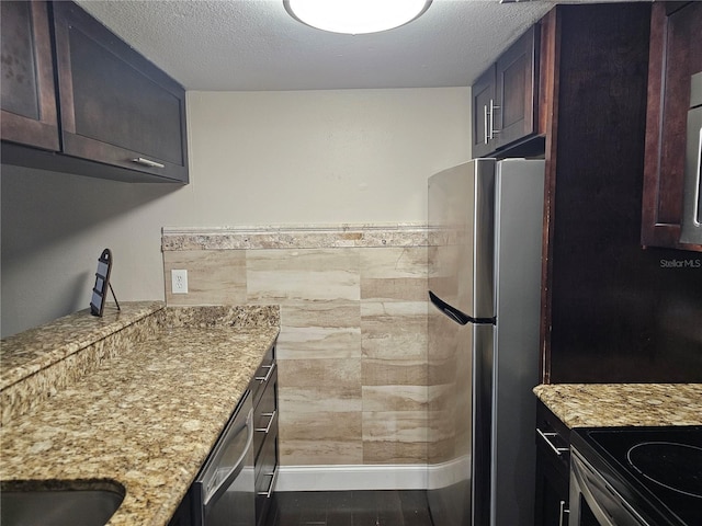 kitchen featuring light stone countertops, stainless steel appliances, and a textured ceiling