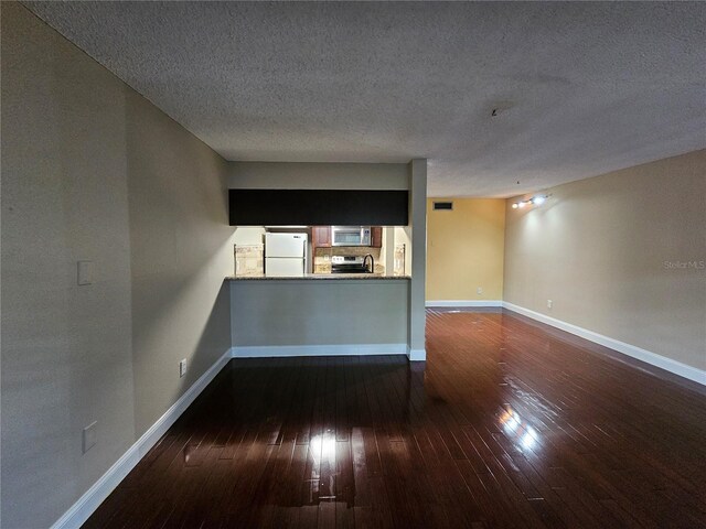 unfurnished living room with visible vents, a textured ceiling, baseboards, and dark wood-style flooring