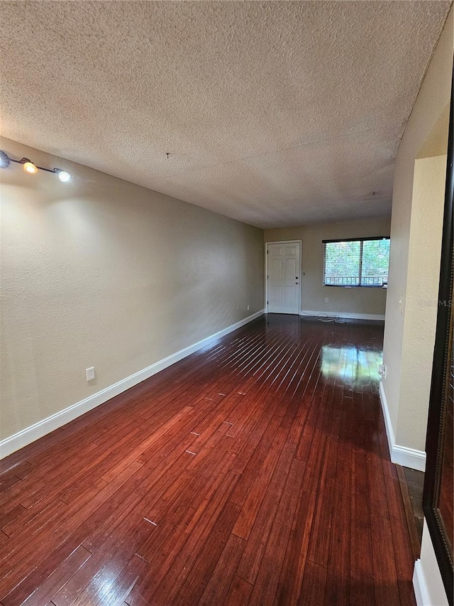 spare room featuring wood-type flooring, baseboards, and a textured ceiling