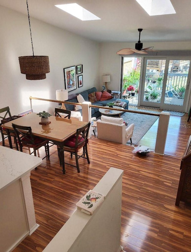 dining area featuring dark hardwood / wood-style flooring, lofted ceiling with skylight, and ceiling fan