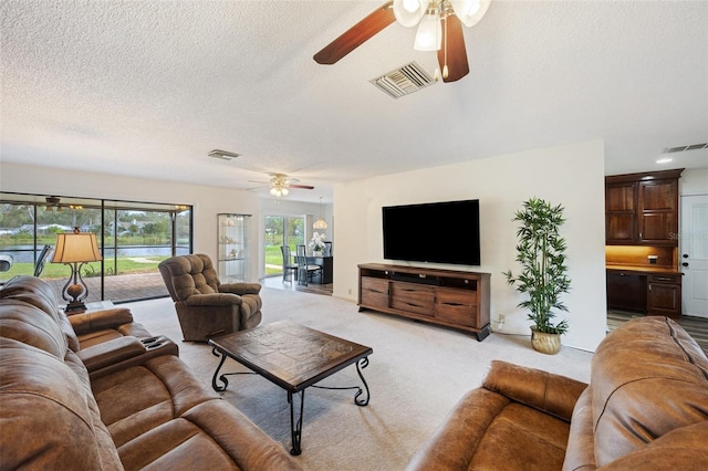 living room with a textured ceiling, light colored carpet, and ceiling fan