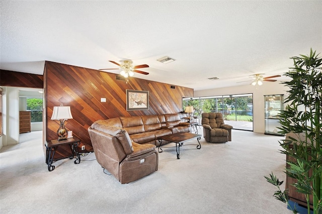 carpeted living room featuring ceiling fan, a textured ceiling, and wooden walls