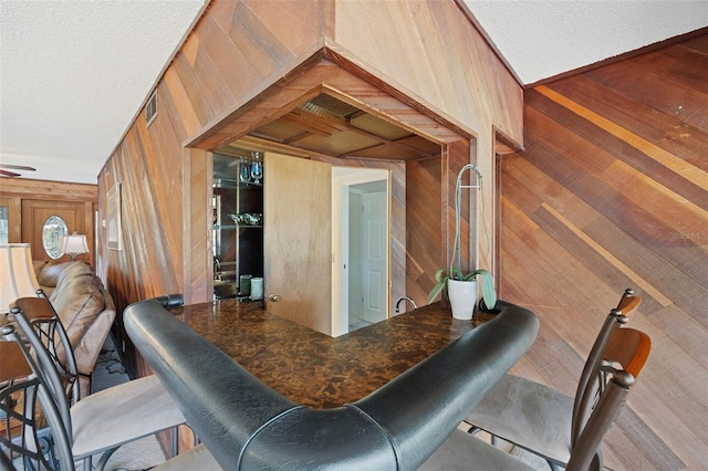 interior space featuring a textured ceiling and wooden walls