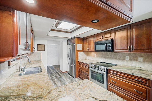 kitchen featuring sink, a tray ceiling, decorative backsplash, appliances with stainless steel finishes, and light wood-type flooring