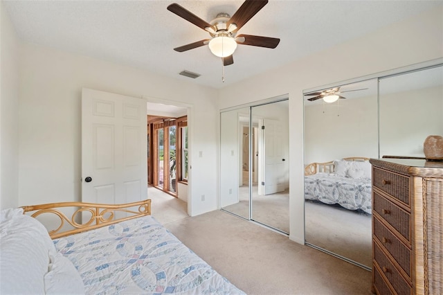 carpeted bedroom featuring multiple closets and ceiling fan