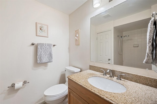 bathroom with a tile shower, vanity, and toilet