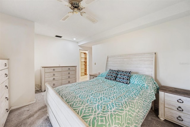 carpeted bedroom with a walk in closet, ceiling fan, and a closet