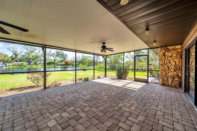 unfurnished sunroom featuring a wealth of natural light, a water view, and ceiling fan