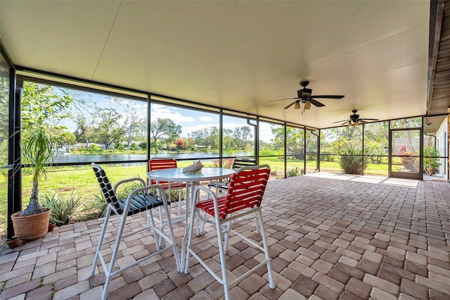 sunroom featuring ceiling fan and a water view