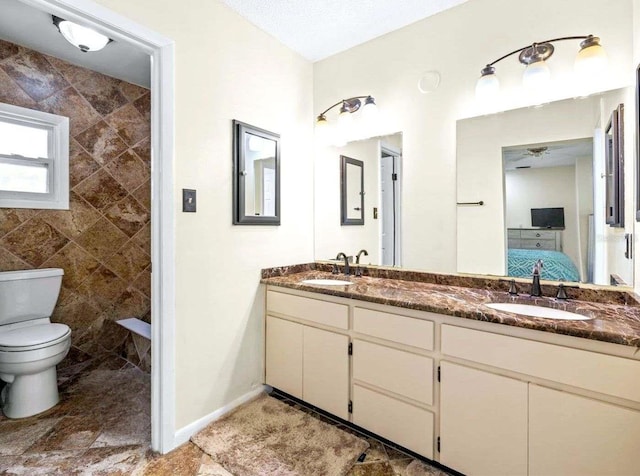 bathroom featuring vanity, ceiling fan, toilet, and tile walls