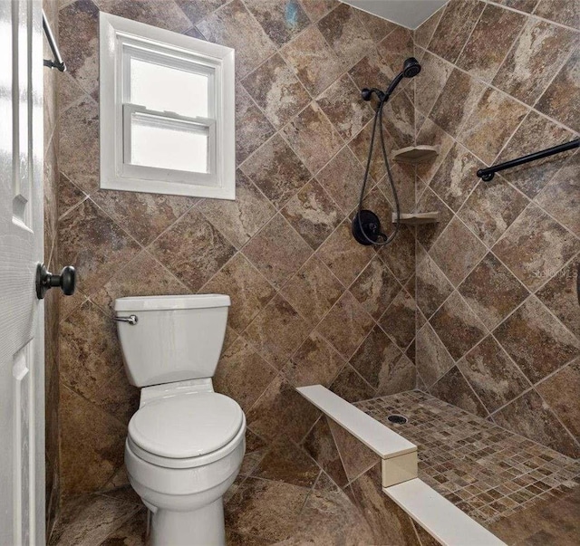 bathroom with toilet, tile walls, and a tile shower