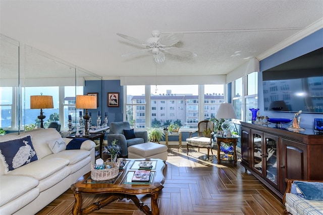 living room with dark parquet flooring, a textured ceiling, ceiling fan, and ornamental molding