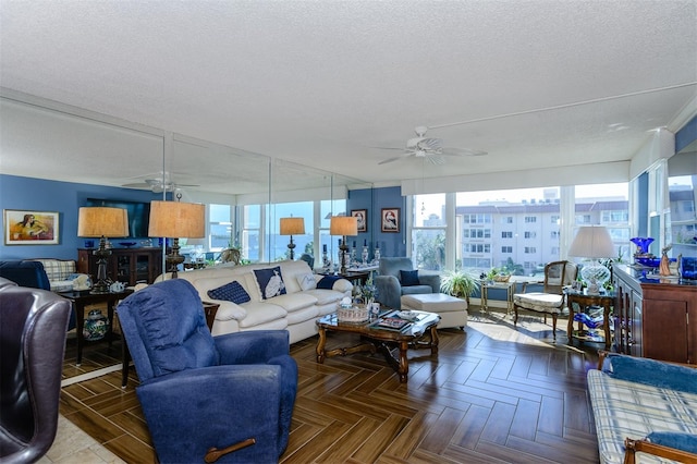 living room with ceiling fan, parquet flooring, a textured ceiling, and a wealth of natural light