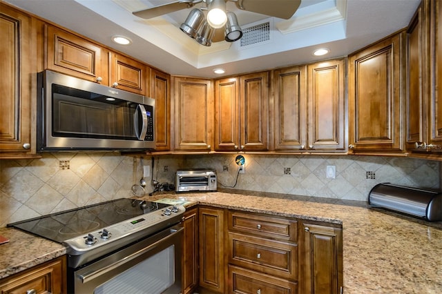 632 Edgewater Dr Unit 532, Dunedin, FL 34698 - kitchen with stainless steel appliances, a ceiling fan, a tray ceiling, brown cabinetry, and recessed lighting