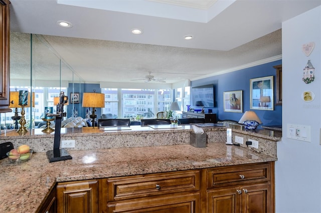 kitchen with a wealth of natural light, crown molding, light stone countertops, and a textured ceiling