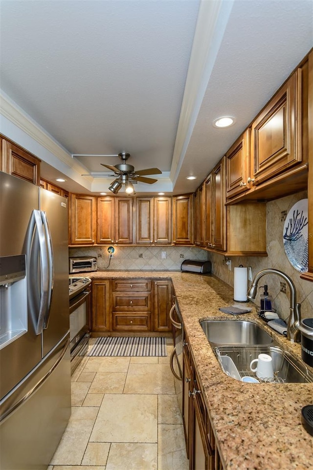 632 Edgewater Dr Unit 532, Dunedin, FL 34698 - kitchen featuring appliances with stainless steel finishes, a sink, brown cabinetry, tasteful backsplash, and a raised ceiling