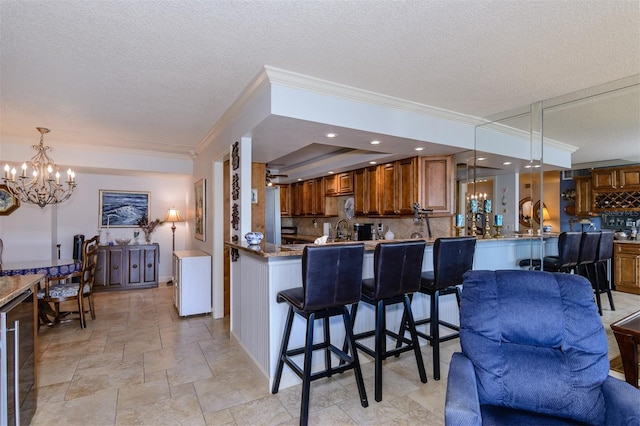 kitchen featuring backsplash, crown molding, decorative light fixtures, a kitchen bar, and kitchen peninsula