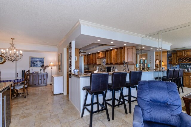 632 Edgewater Dr Unit 532, Dunedin, FL 34698 - kitchen with brown cabinetry, beverage cooler, crown molding, a chandelier, and a textured ceiling