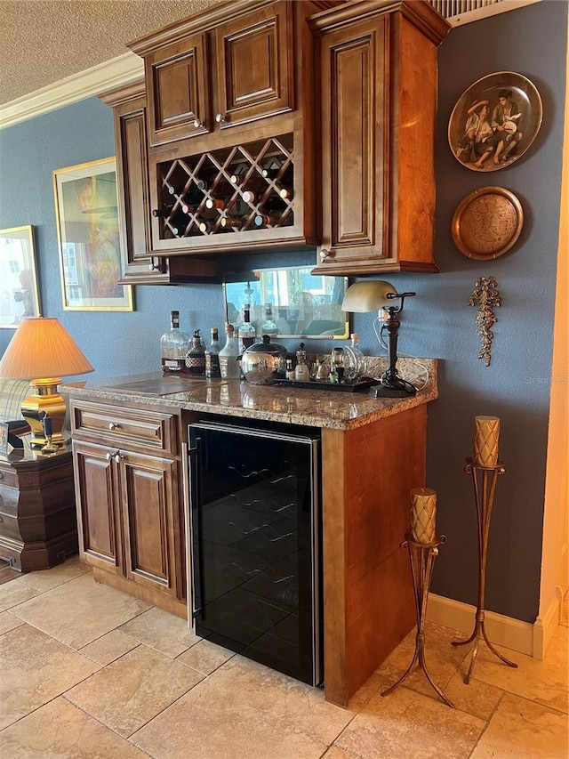 bar featuring dark stone countertops, crown molding, beverage cooler, and a textured ceiling