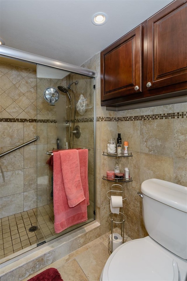 bathroom featuring a shower with shower door and toilet