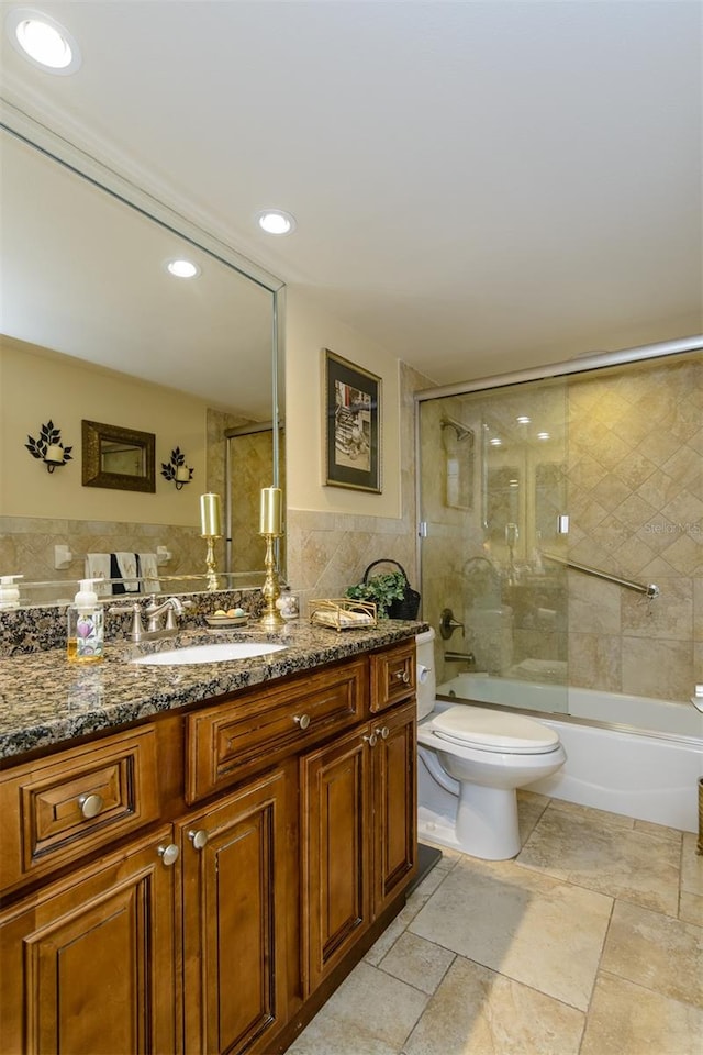 full bathroom with toilet, vanity, tile walls, and combined bath / shower with glass door