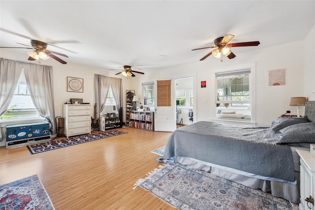 bedroom featuring hardwood / wood-style flooring, ceiling fan, and multiple windows