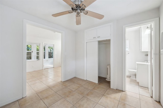 unfurnished bedroom with ceiling fan, connected bathroom, a closet, and light tile patterned floors