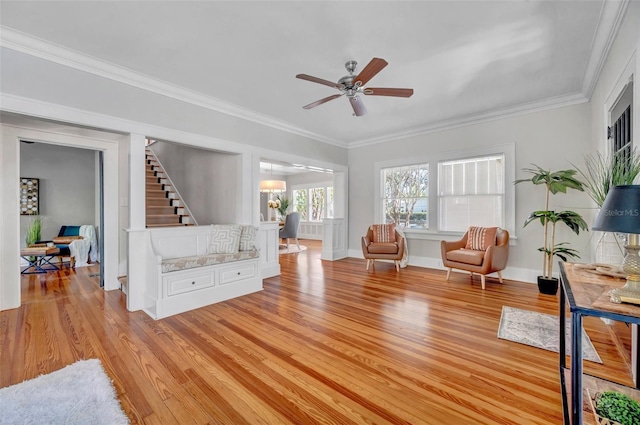 living room featuring ornamental molding, light hardwood / wood-style floors, and ceiling fan