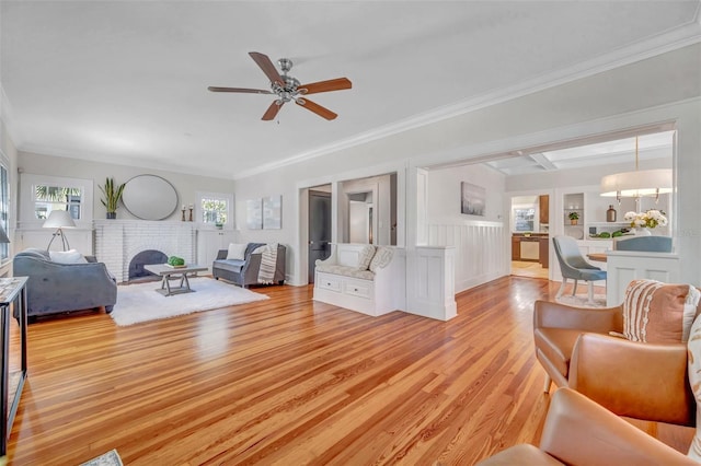 living room with ornamental molding, ceiling fan, a fireplace, and light hardwood / wood-style flooring