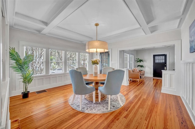 dining space with beamed ceiling, coffered ceiling, and light hardwood / wood-style floors